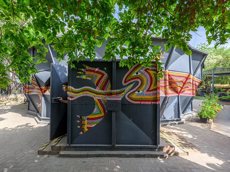 The Darwin Bucky pavilion becomes a canvas of cultural convergence as Gond artists adorn its geometric facade with a vibrant mythological lizard. (Image Credits: Vinay Panjwani)
