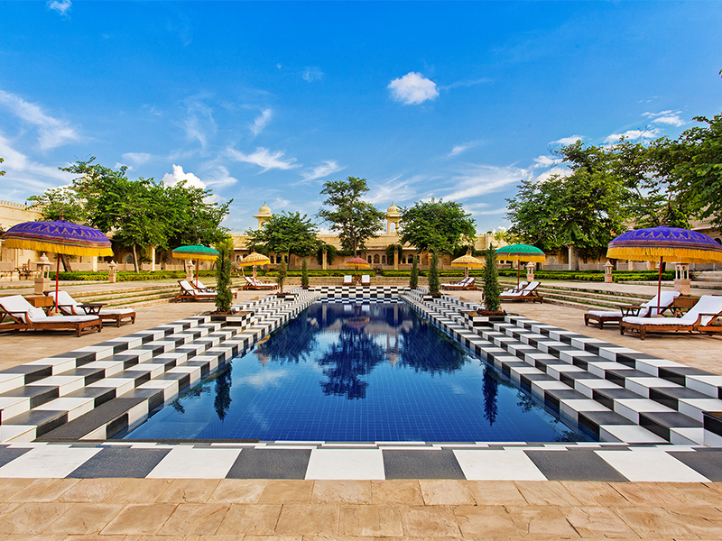 The pool with its chequered tiles is surrounded by arched corridors and towering chhatris. (Image Credits: Courtesy of Udaivilas)
