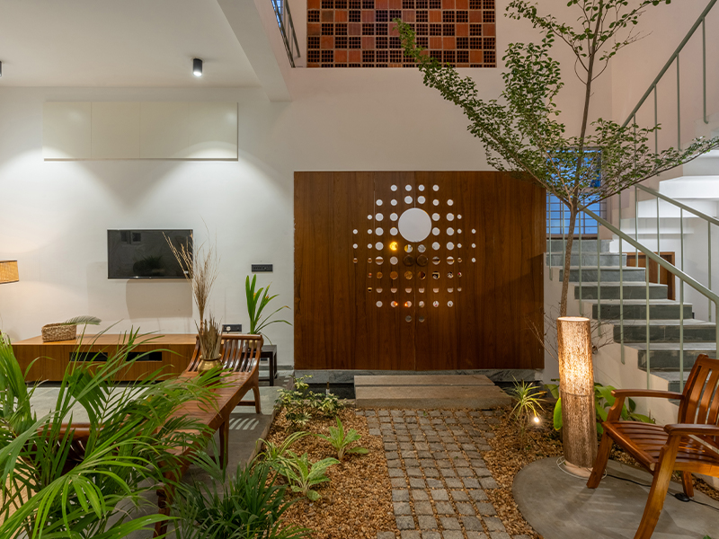 The Soul(talks) residence embodies biophilic living, where greenery thrives alongside earthy textures. Warm wood pieces from Capital Grand Furniture, Coimbatore, and rustic lamps by Auro Bala Lampshades, Auroville, echo the home’s grounded, nature integration. (Image Credit: Priyanka Rajan)
