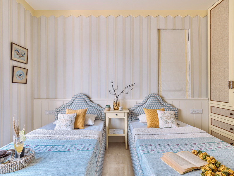 This cottagecore retreat, featuring calming hues with a side of cosy nostalgia, houses bespoke furniture, bedding and cushions from Homestop, pinstripes wallpaper, glass vases from Home Centre and petite vases from IKEA. (Image Credits: Inclined Studio)

