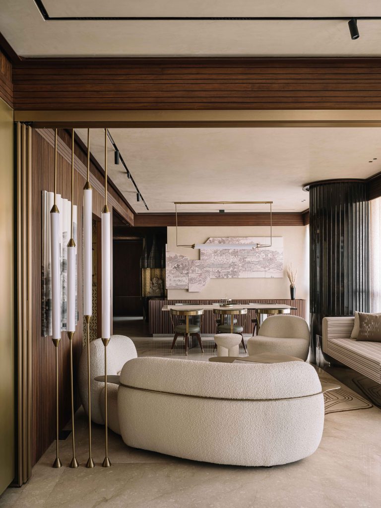 The home features an L-shaped layout, thoughtfully dividing the publicly accessible areas from the private zones, with a plush bouclé couch, armchairs and curated wall art in the dining area from Poshway, adding texture and visual rhythm to the spaces. (Image Credits: Ishita Sitwala)