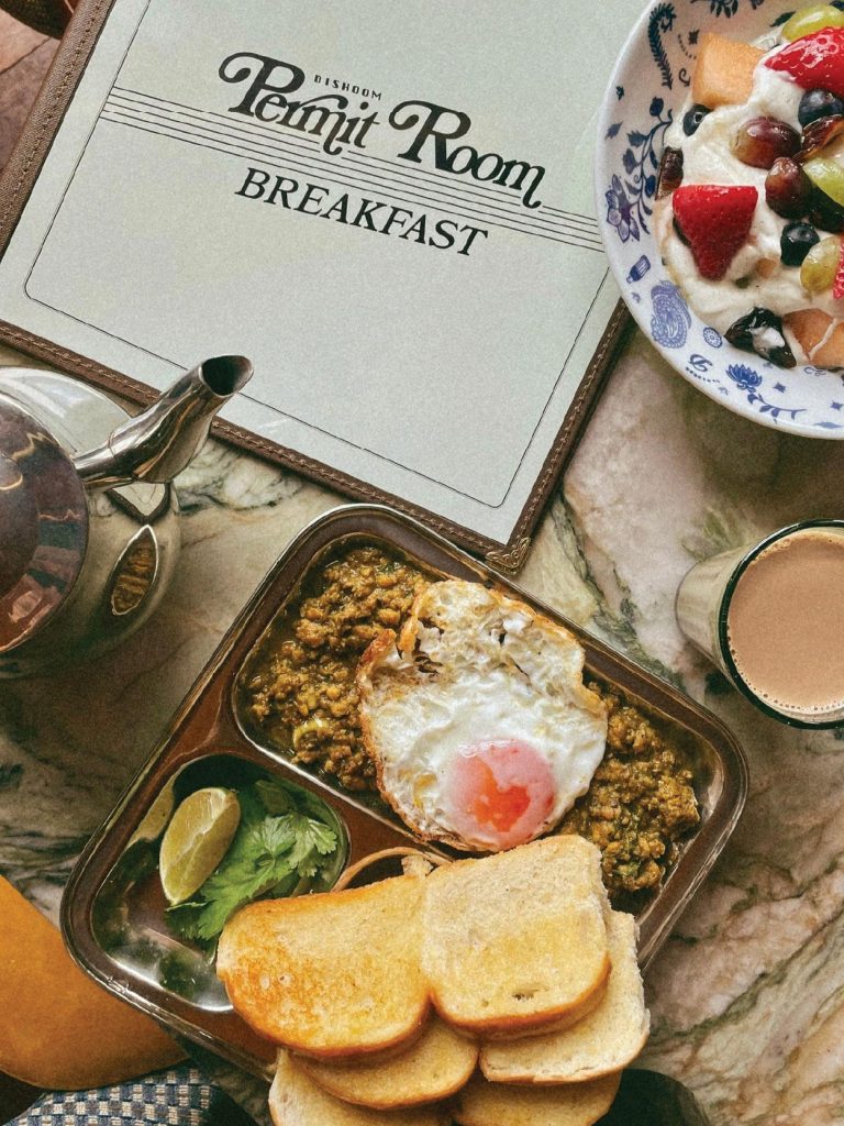The ‘Full Permit’ breakfast is Dishoom’s take on the classic Bombay fry-up — a hearty spread of spiced akuri (scrambled eggs), streaky bacon, pork sausages, and more of that irresistibly buttery pau. (Image Credit: Permit Room Lodgings)