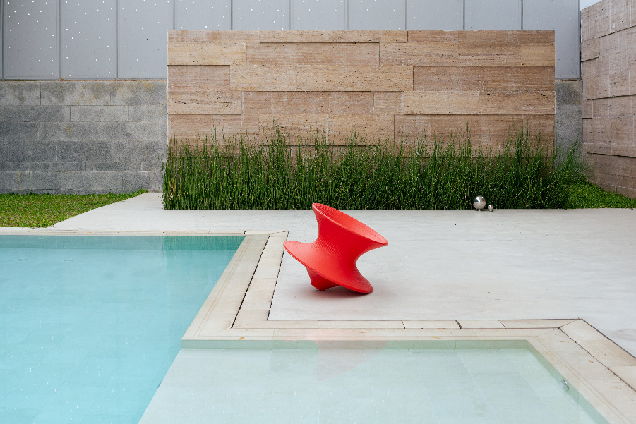 The pool deck uses concrete flooring by Stefano, while the water body itself has been constructed by Mission Pools. The vibrant red Spun Chair by Thomas Heatherwick adds a cheeky accent to the setting. Tiles are sourced from Rosa Gres. Completing the scene are custom-made stainless steel spheres by Kiasma Studio, their Dali-like, topsy-turvy reflections playfully distorting the landscape. (Image Credit: Vivek Eadra)