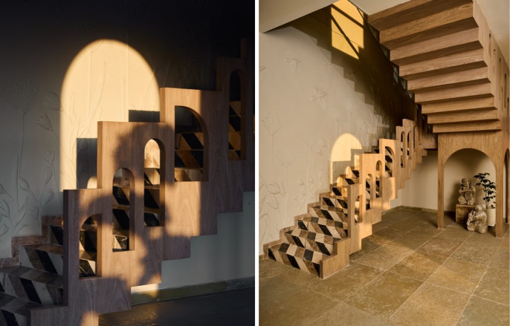 A sculptural staircase by Aarti Dhariwal stands out as a central design feature, showcasing intricate stone inlay, Tuscan-style wooden arches, and detailed relief work inspired by the surrounding natural landscape. (Image Credits: The Matter Studio)
