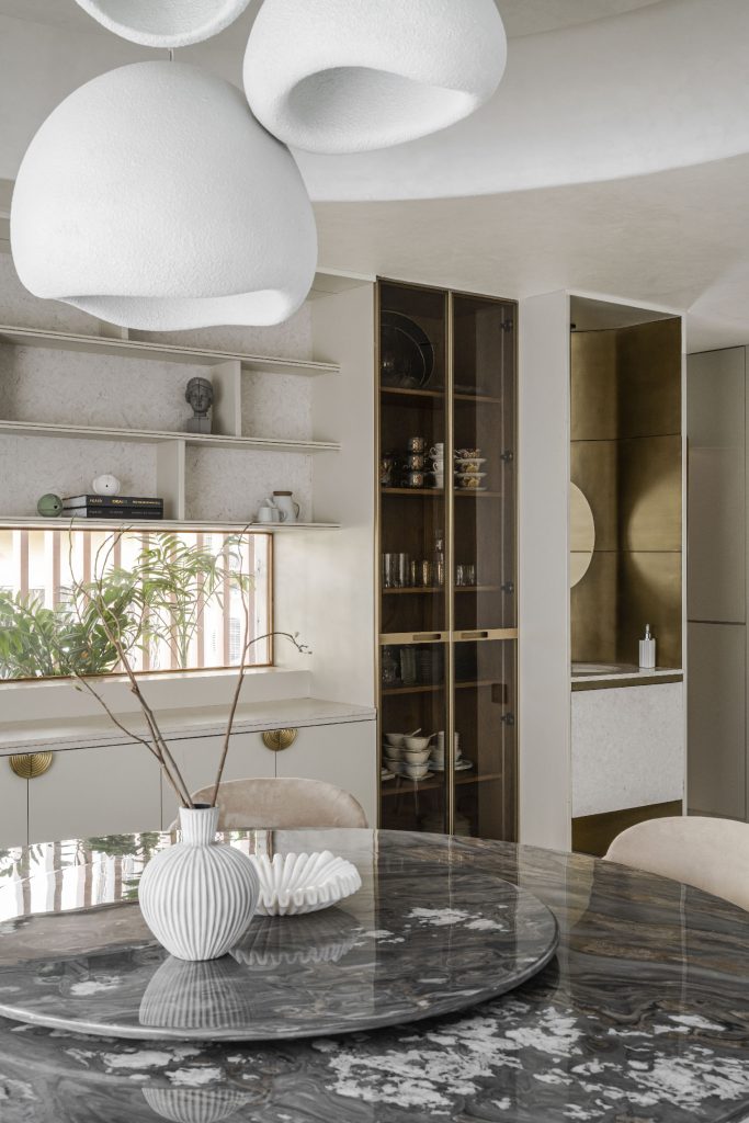 The House of Curve, designed by Terra Firma, the crockery unit from KOIL, Quartz by Kalinga Stone, beautifully harmonising sculptures by Claymen and All About Living, with organically shaped lighting from All About Living, establish a visual link between the dining area and the kitchen. (Image Credit: MKG Studios)