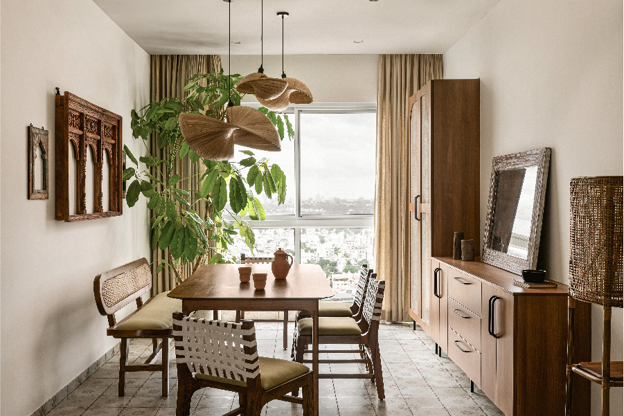 The dining room is imagined as a heartfelt blend of nostalgia and contemporary calm. The floral floor tiles in muted tones and a planter add a layer of life and rhythm. The dining table, chairs and crockery unit were custom-designed and built on-site. The wooden mirror is from Bangalore Hunts. (Image Credits: Nayan Soni)