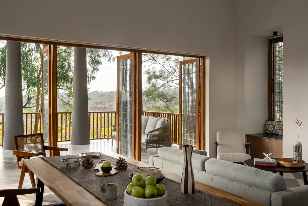 The living and dining areas seamlessly spill out onto the verandah, creating an effortless flow of conversation, adorned with vases and bowls from Ware Innovations. (Image Credits: Ekansh Goel) 
