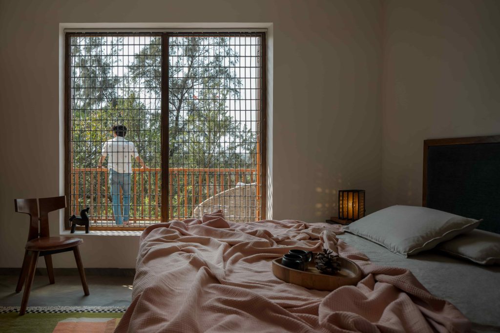 The bedroom holds a wooden bed, a side table and a wooden chair from Freedom Tree and Ikea, while a verdant rug underfoot from Saphed Home adds a sense of warmth, and the lamp is from The Black Steel. (Image Credits: Ekansh Goel)
