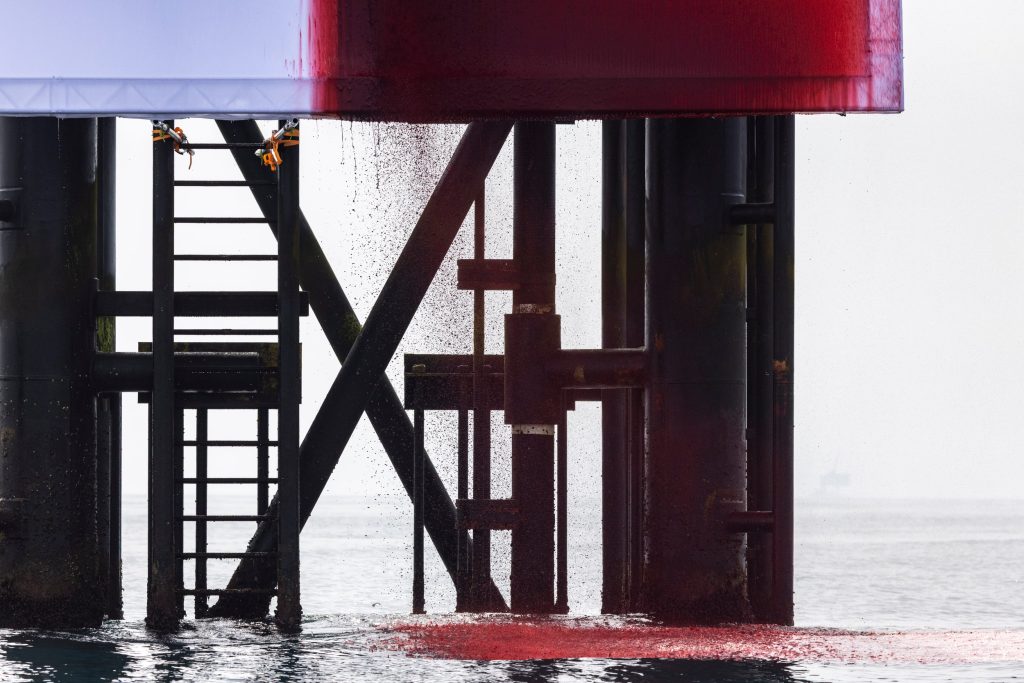 The cascading red liquid spills like a torrent of blood, vividly symbolising the planet’s suffering. (Image Credits: Greenpeace)

