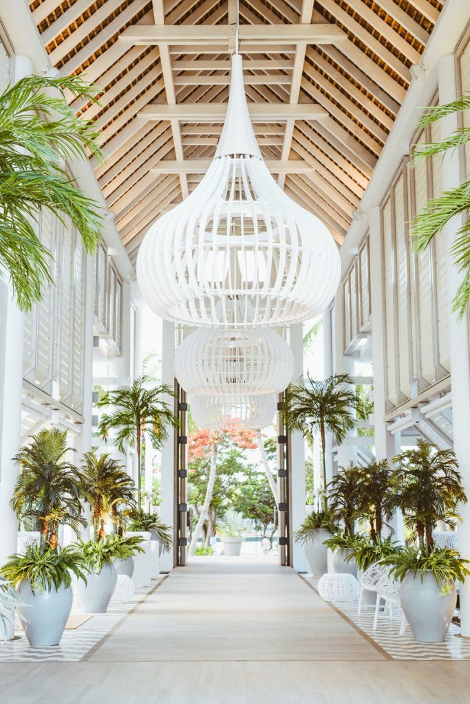 Every detail of the island comes alive in the lobby, where soaring white wooden rafters, crisp shutters, and oversized planters create an airy, island-chic welcome. (Image Credit: LUX* Grand Gaube)