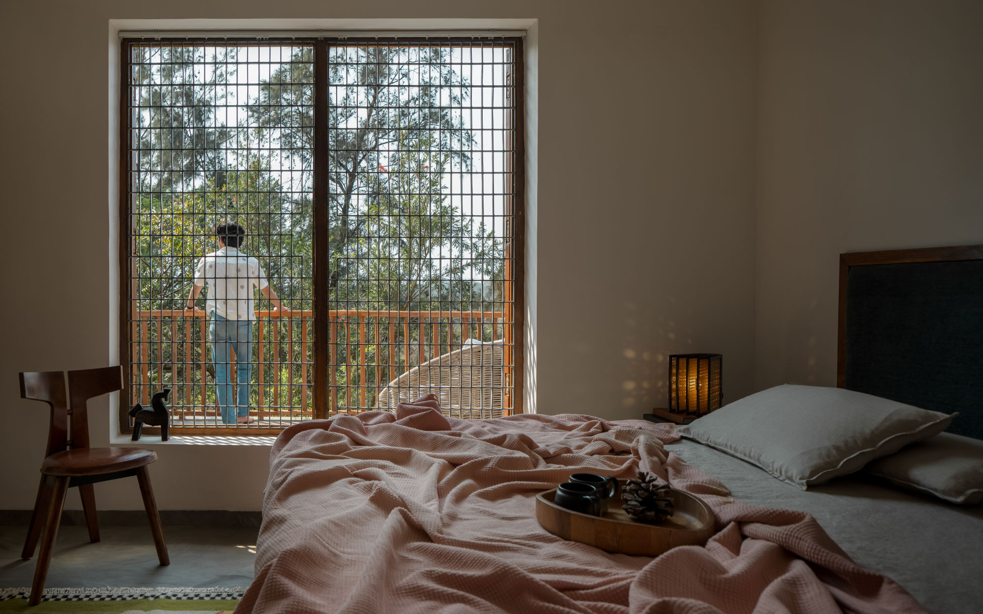 The bedroom holds a wooden bed, a side table and a wooden chair from Freedom Tree and Ikea, while a verdant rug underfoot from Saphed Home adds a sense of warmth, and the lamp is from The Black Steel. (Image Credits: Ekansh Goel)