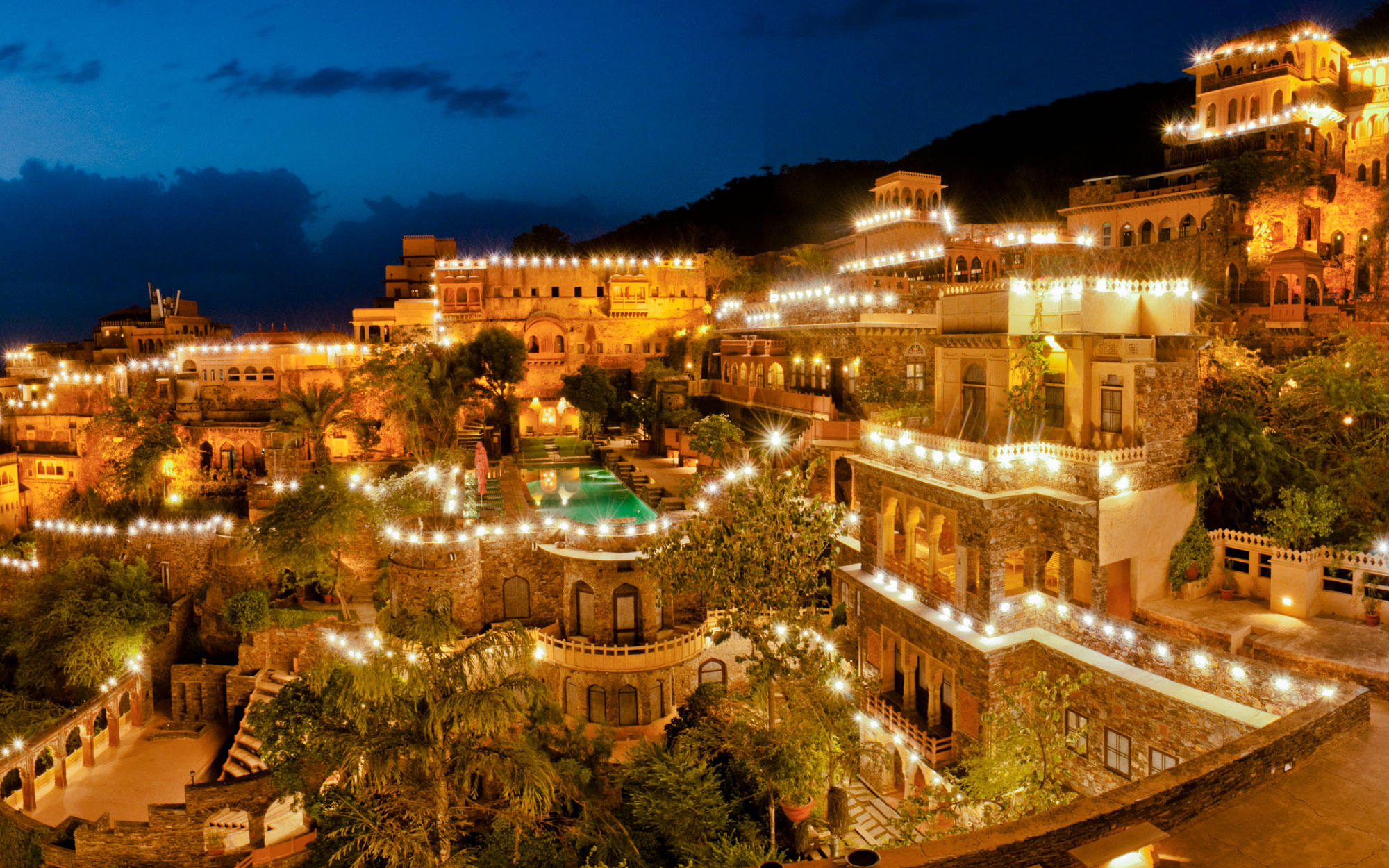 The scalloped arches, alcoves, intricate door screen and natural materials imbue a sense of Rajasthani design. (Image Credits: Courtesy of Neemrana Fort Palace)
