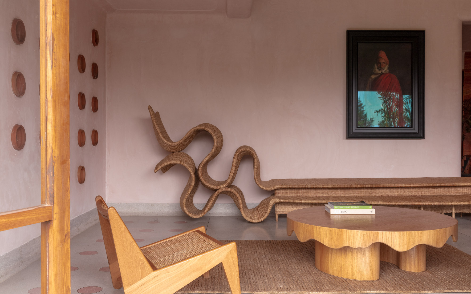 The living area opens into a lush green garden and is conceptualised to be a blend of the past and present. It features a sculptural wicker bench from The Wicker Story and the Terracotta-rimmed circular wall apertures by Ara Living. (Image Credit: Pankaj Anand)