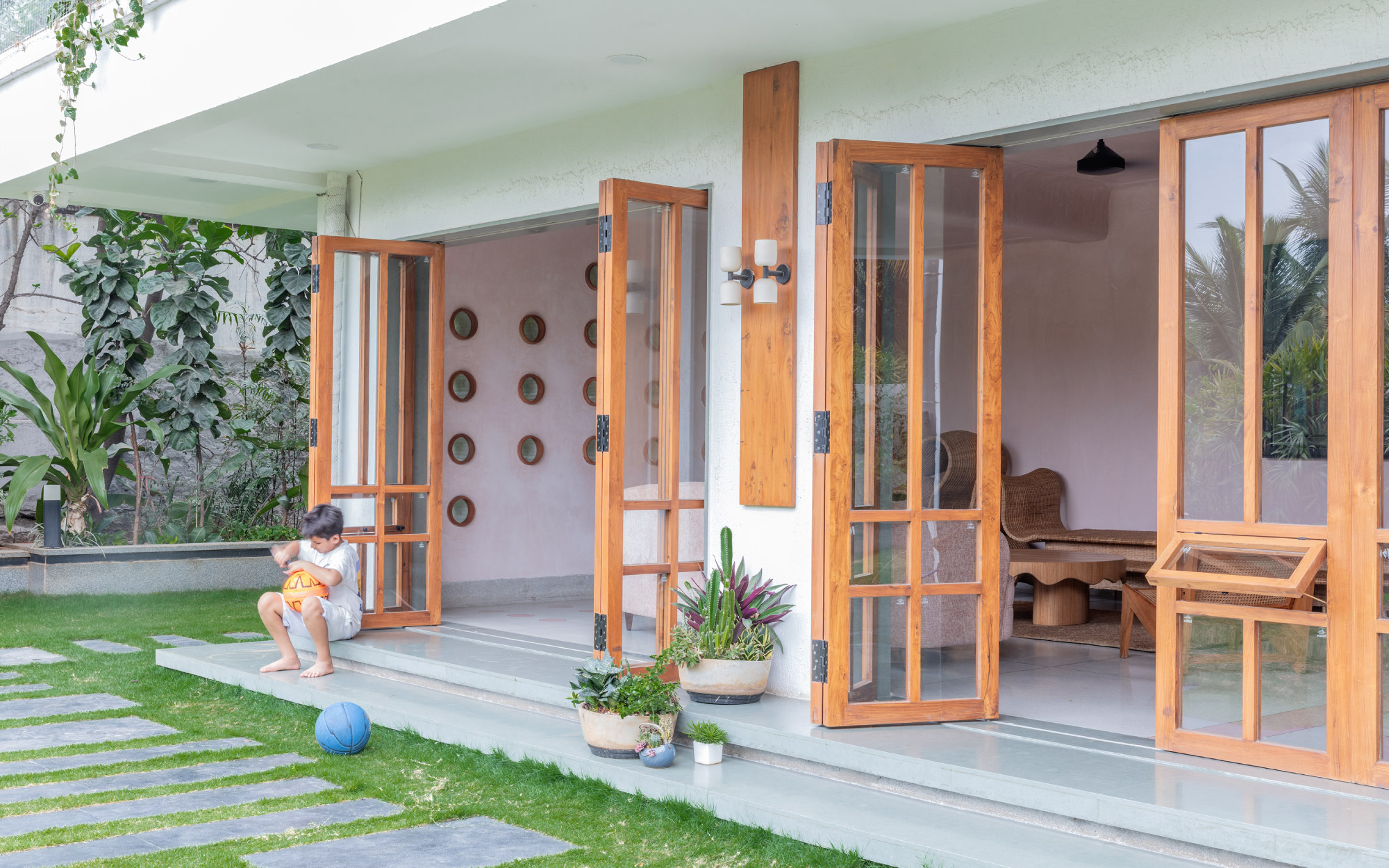 The home’s living spaces feature wood-framed glass doors and windows that blur the boundaries of the indoors and outdoors. (Image Credit: Pankaj Anand)