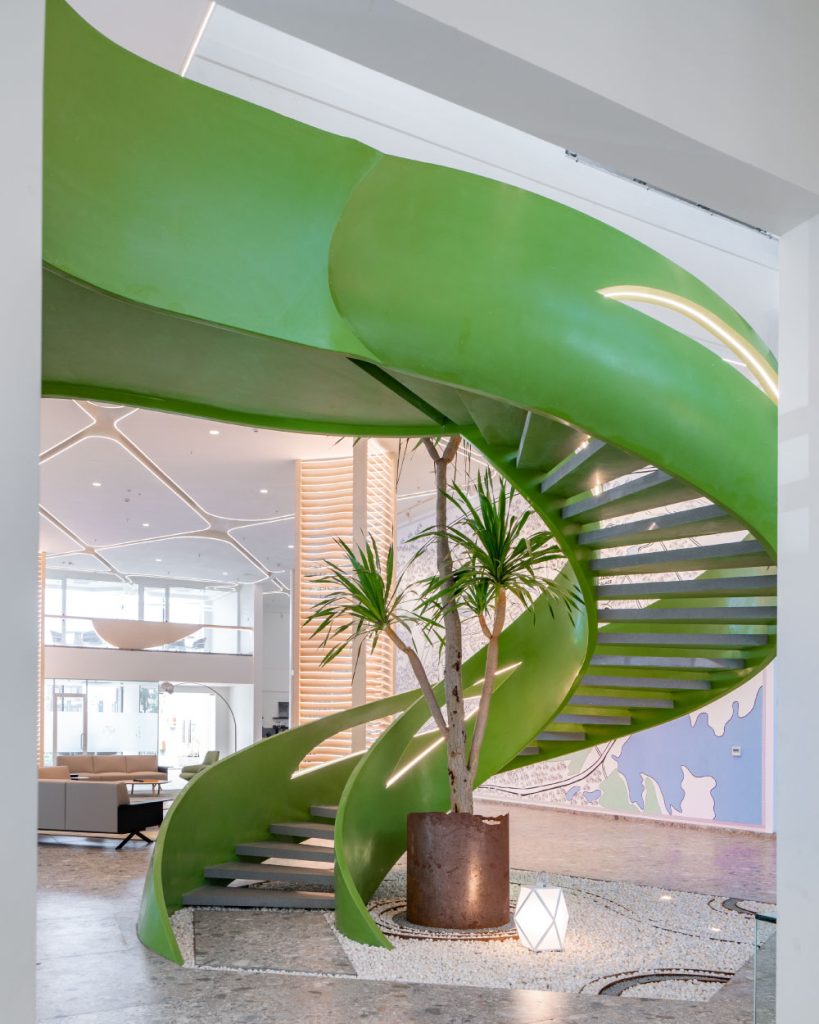 The lime green staircase sweeps upward like a sculptural ribbon, anchoring the space. (Image Credits: The World Experience Centre)