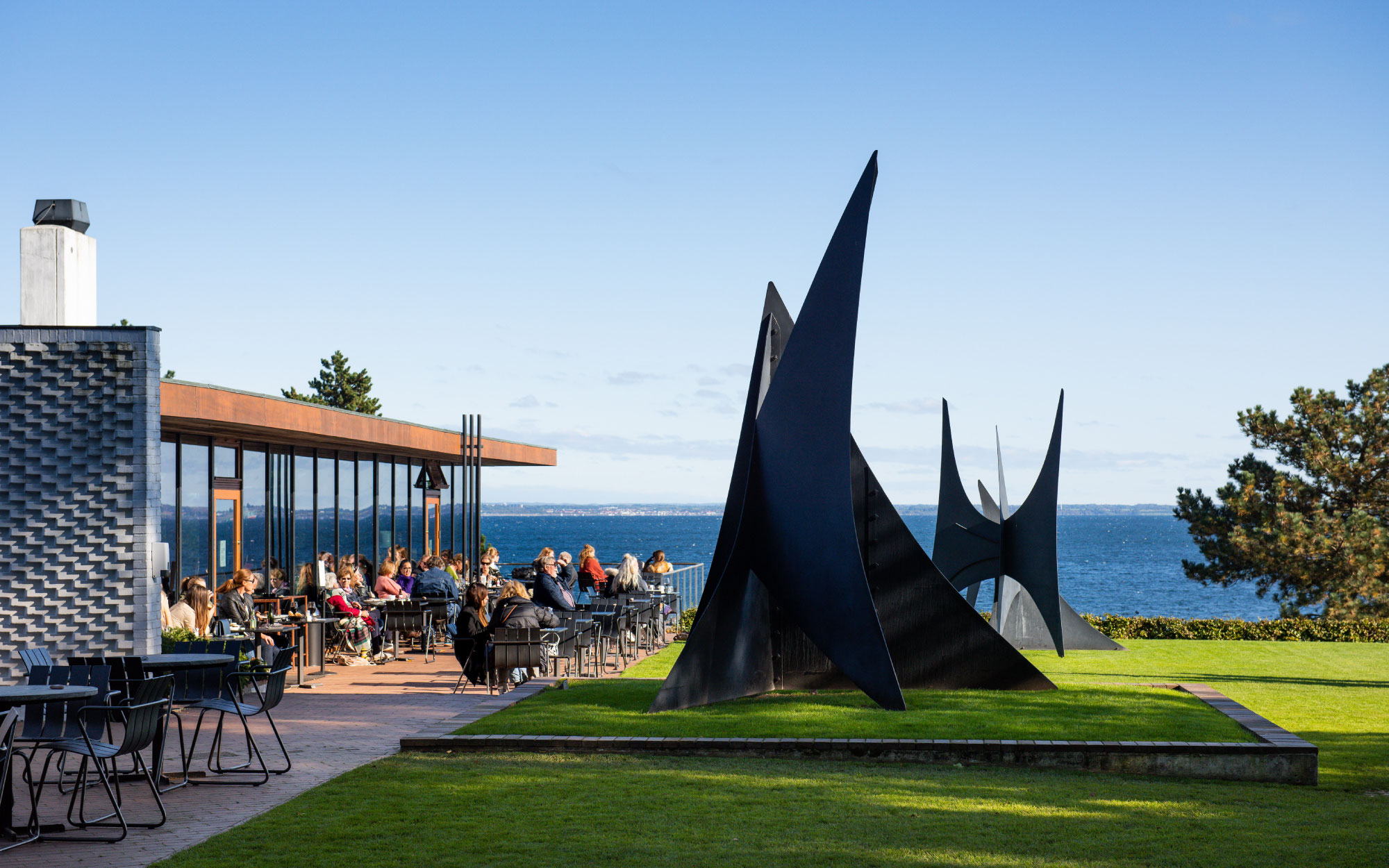 The Louisiana Café offers both elegant indoor dining framed by glass walls and alfresco seating on the terrace, paired with sweeping views of Alexander Calder’s majestic sculptures on the iconic Calder Terrace. (Image Credit: Kim Hansen)