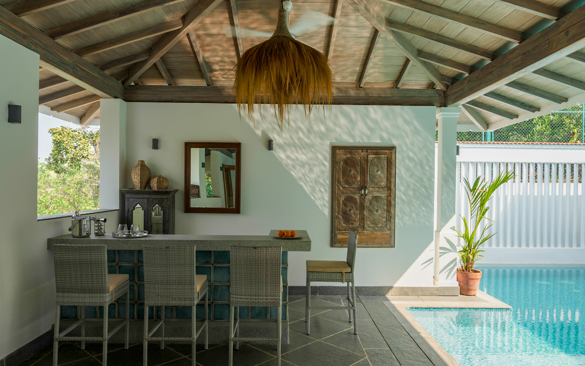 This poolside alcove is enhanced by sloping roofs, wooden windows for decorative charm, and an organic light fixture sourced from Rangeela, another of Ritu's favourite stores in Goa. (Image Credits: Graf Media)