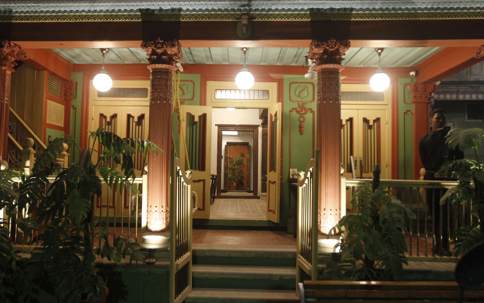 The verdant and crimson facade at Mangaldas Ni Haveli II features ornate columns and stucco work. (Image Credits: Courtesy of the House Of MG)