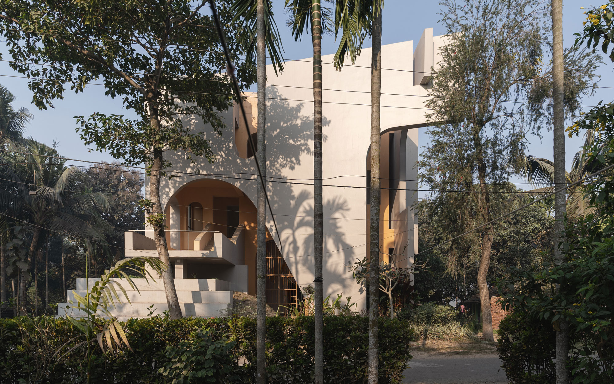 The sculpted façade, with its terracotta-hued massing and irregular arched cut-outs, evokes Bengal’s temple architecture. (Image Credits: Syam Sreeylam)