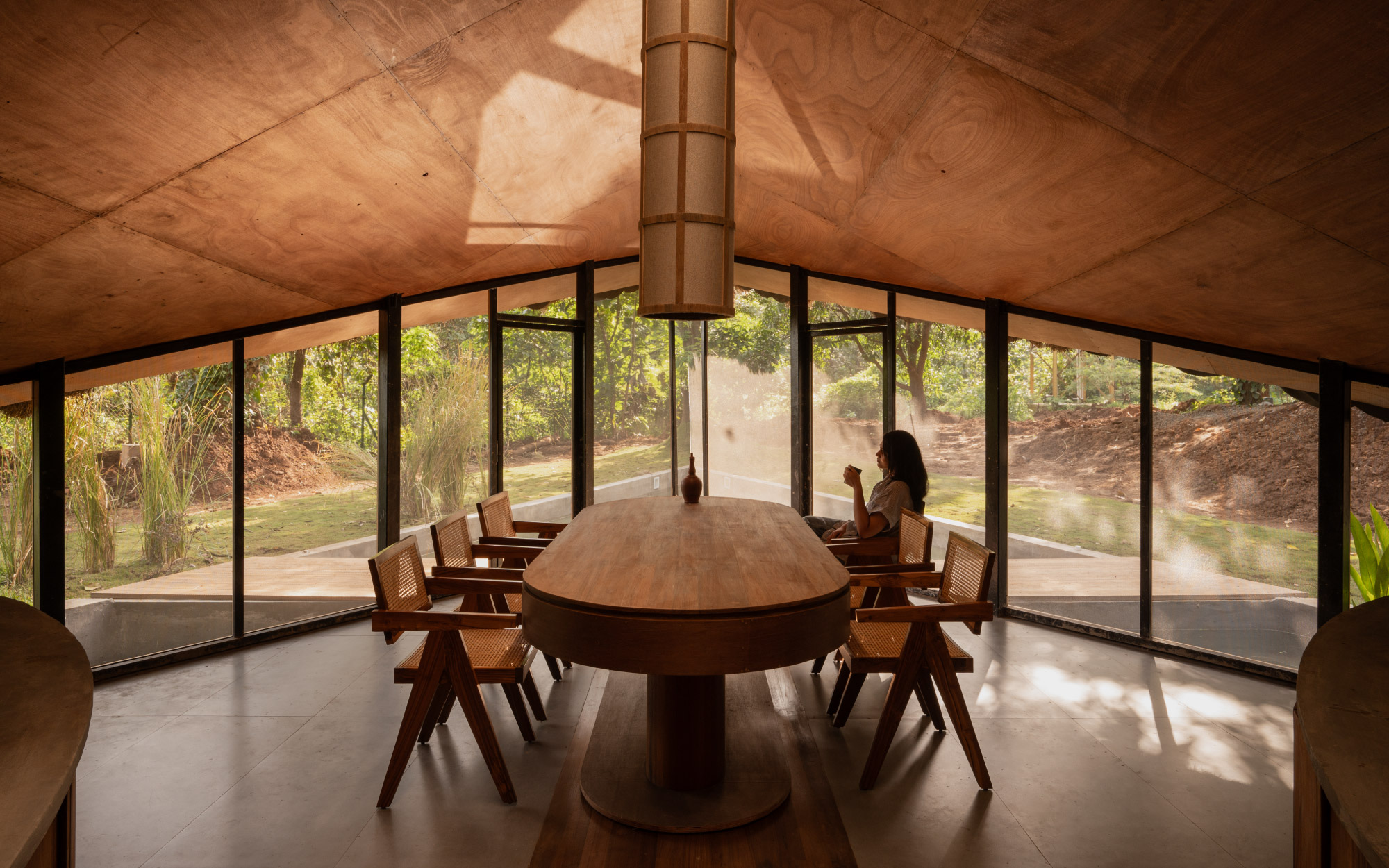 A cosy dining area, wrapped in wooden accents and glass, maintains a dialogue with both the surrounding landscape and the triangular pool beyond. (Image Credits: Studio IKSHA)