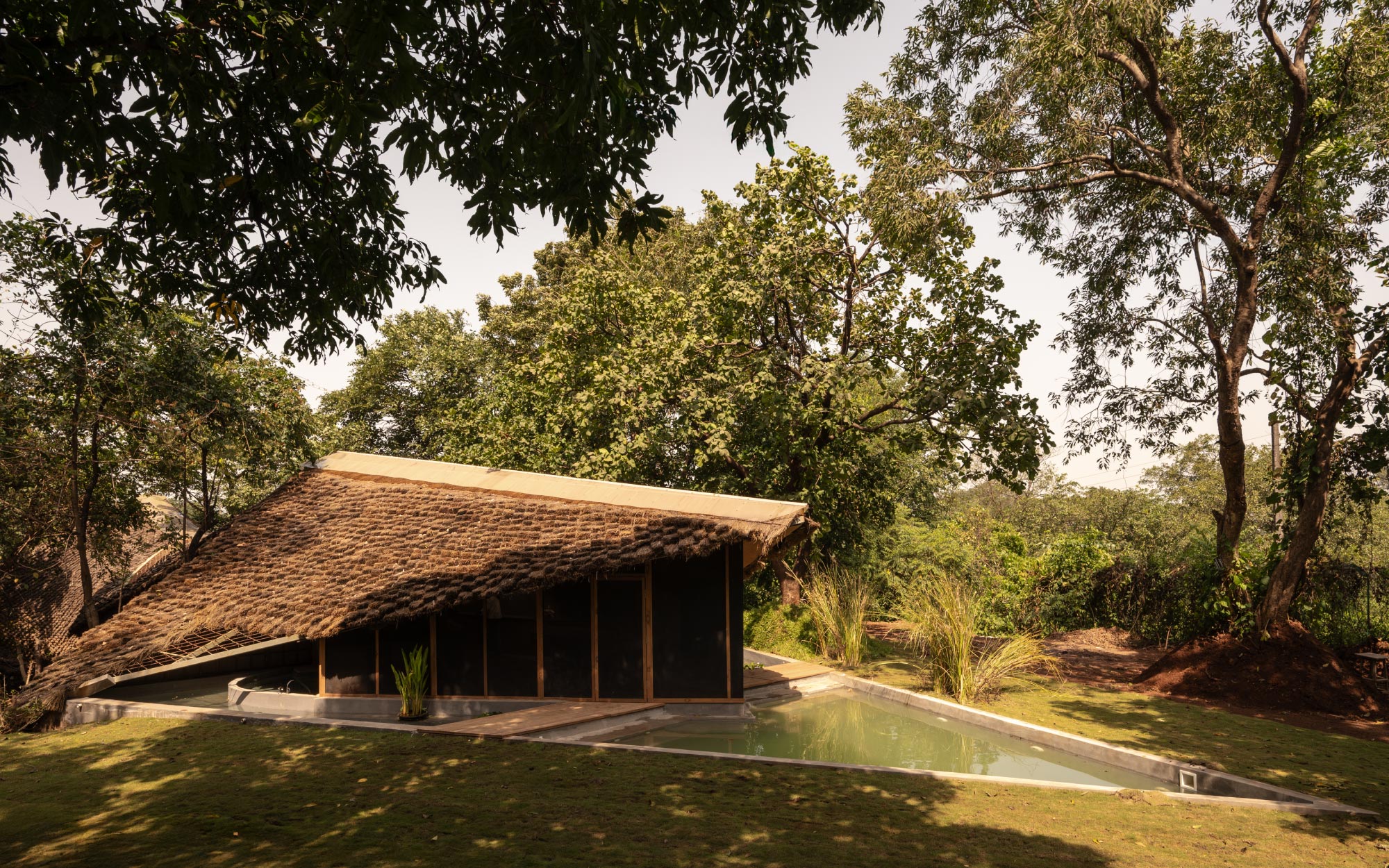 The home’s elongated form traces the contours of the terrain, while a slender swimming pool mirrors the stream below. (Image Credits: Studio IKSHA)