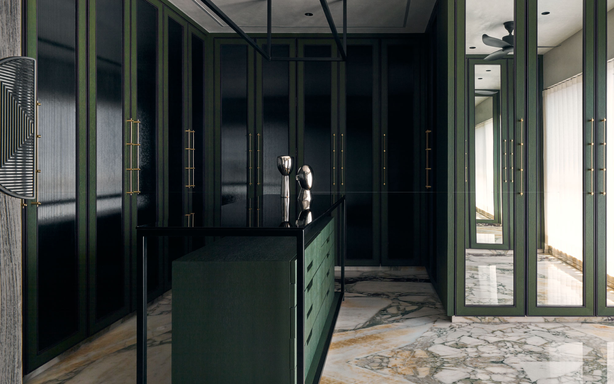 Drenched in a deep olive palette and anchored by boldly veined marble underfoot, the walk-in wardrobe exudes a poised and timeless elegance. (Image Credits: Gokul Rao Kadam)