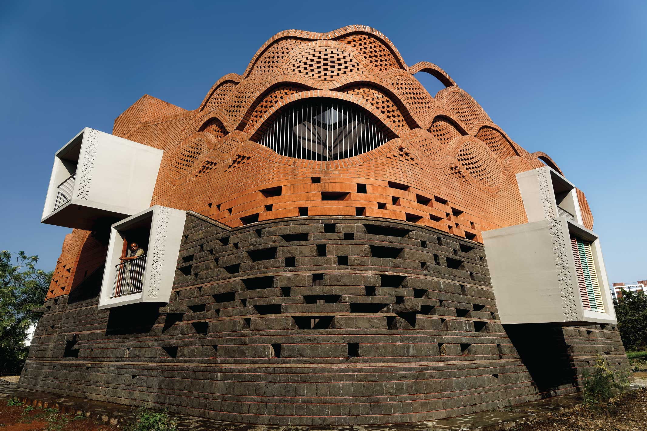A rhythmic play of curved brickwork softens the fortress-like envelope of Gadi House. (Image Credits: Hemant Patil)