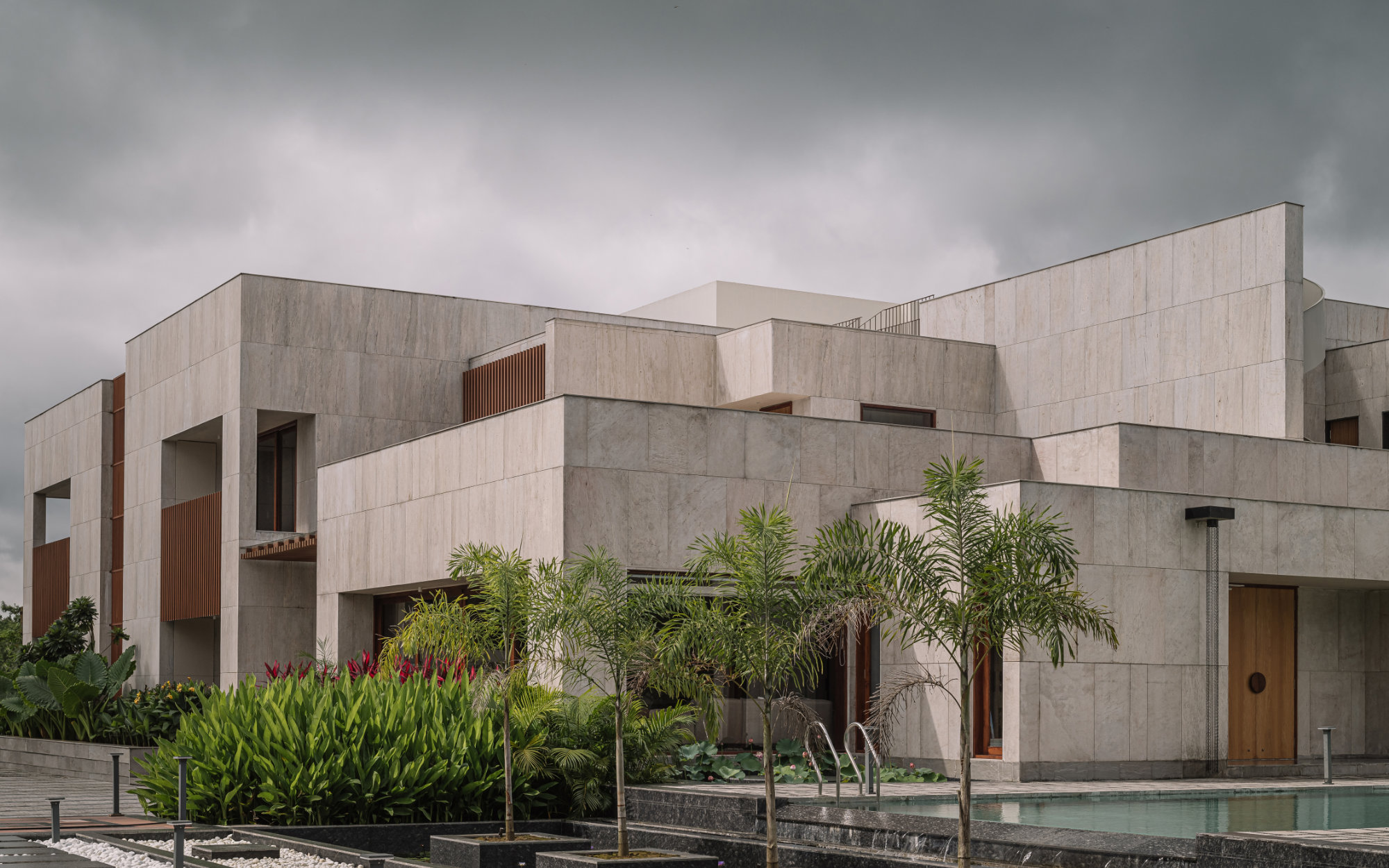 Set within verdant orchards, this home explores materiality and form, balancing structure with its natural surroundings. (Image Credits: Ishita Sitwala)
