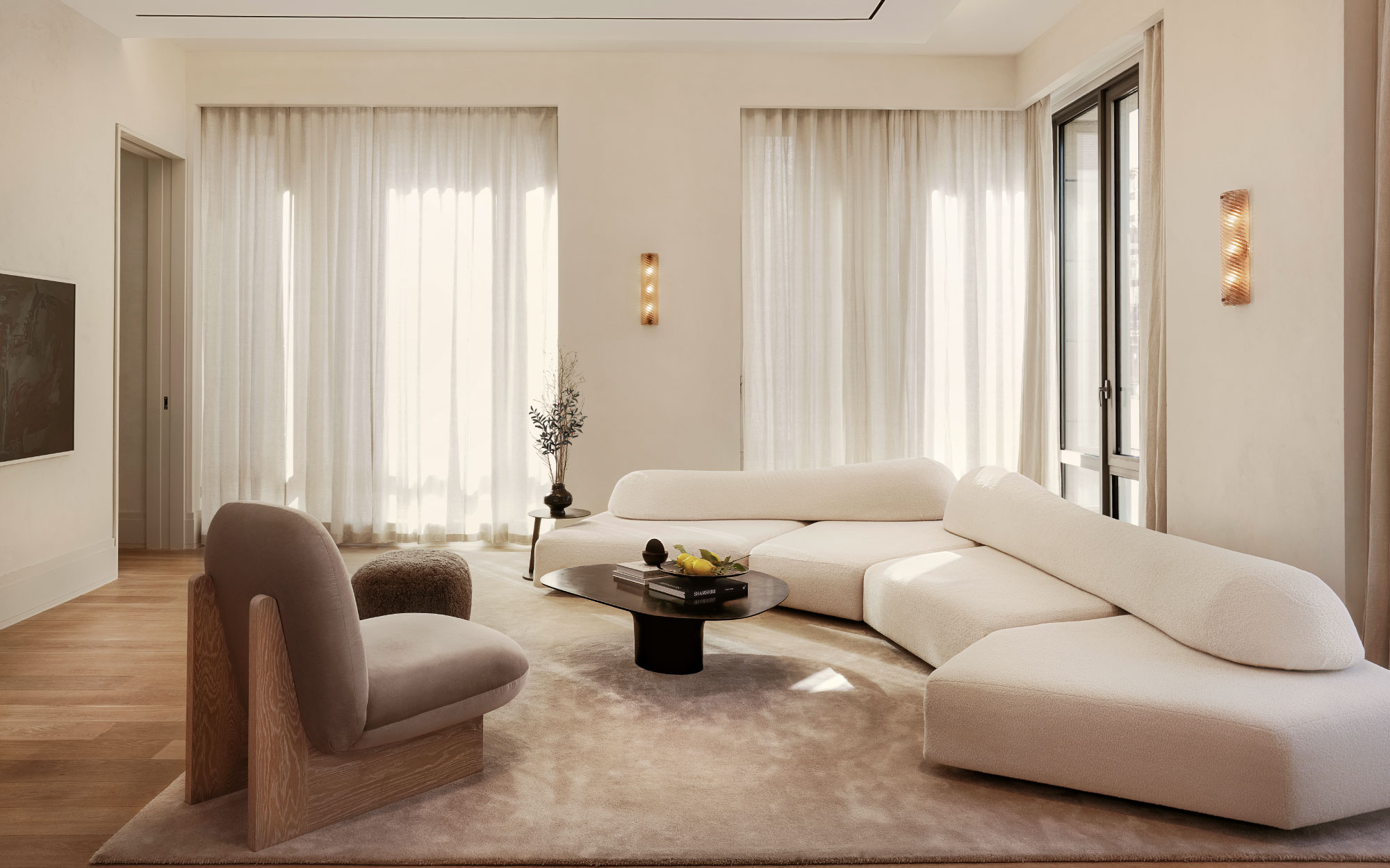 The lounge at Jains Residence is a minimalist viewing room with Murano glass sconces, On the Rocks sofa by Francesco Binfaré for Edra, a glossy NR 2 Liquid Metal Coffee Table, paired with pouffes upholstered in sheepskin. (Image Credits: Gari Markarian)