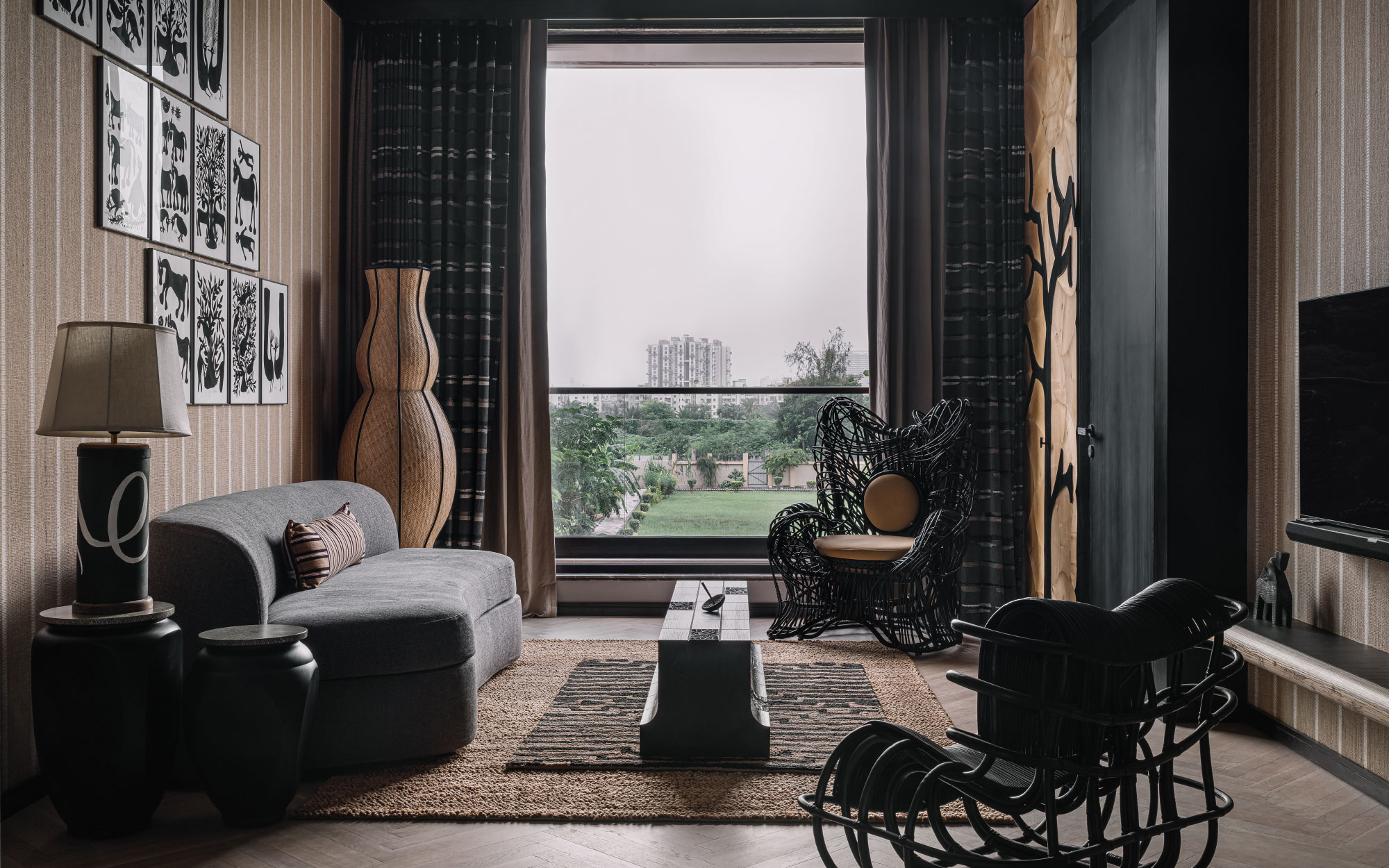 The den in this home inherits a darker tone, with a sofabed from Lago, a lamp from Nilaya Anthology, a cushion from Nomad and a totem from Within, while the monochrome wall art is from Inherited Arts Forum. The obsidian dystopian armchairs against the tree motif inlaid are from QX – Design. (Image Credits: Ishita Sitwala)