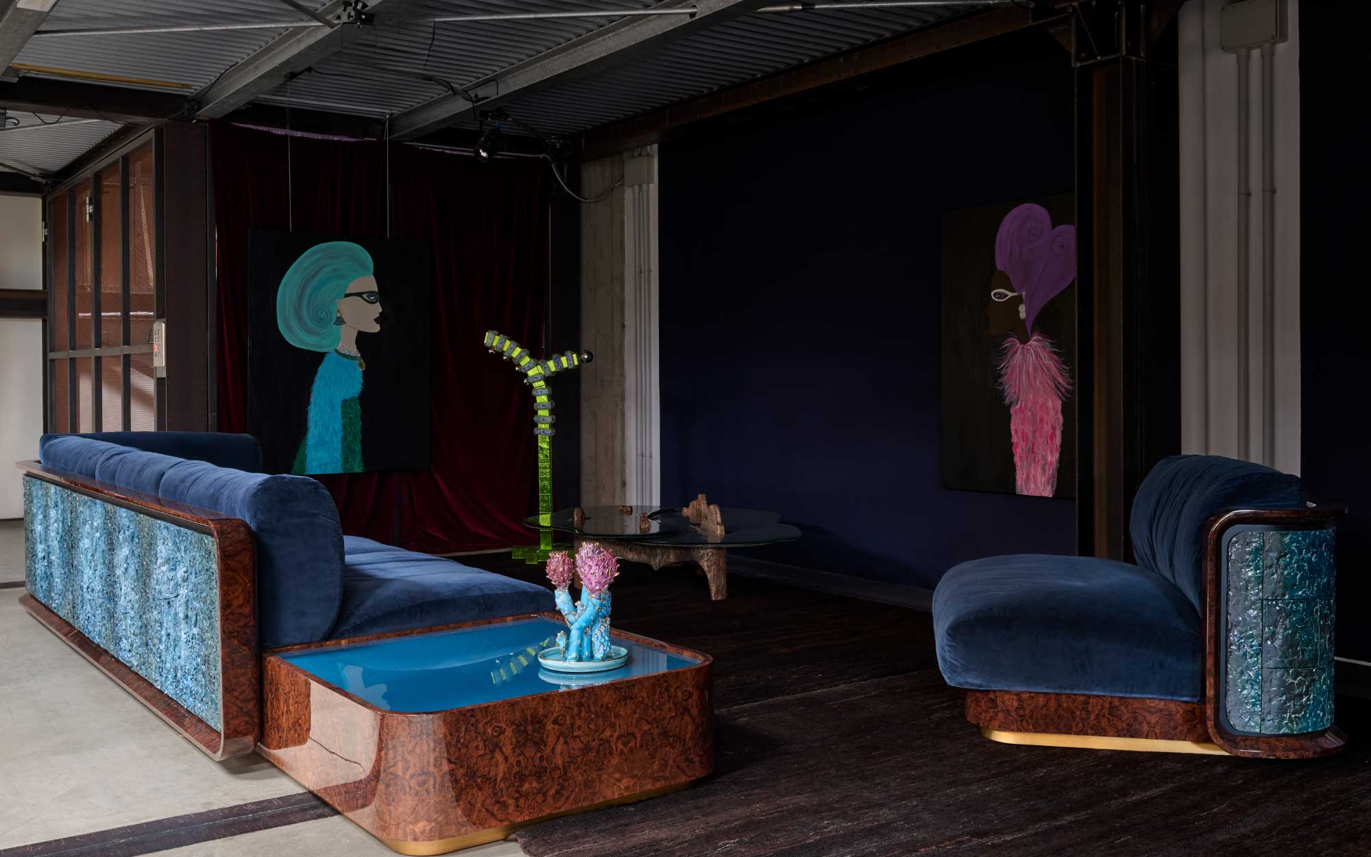 A shared room brings together Rebecca Moses’ narrative paintings, Etereo’s sculptural seating, and Lucia Massari’s playful Murano glass lighting, creating a vivid dialogue between image, object, and illumination. (Image Credits: Filippo Pincolini)