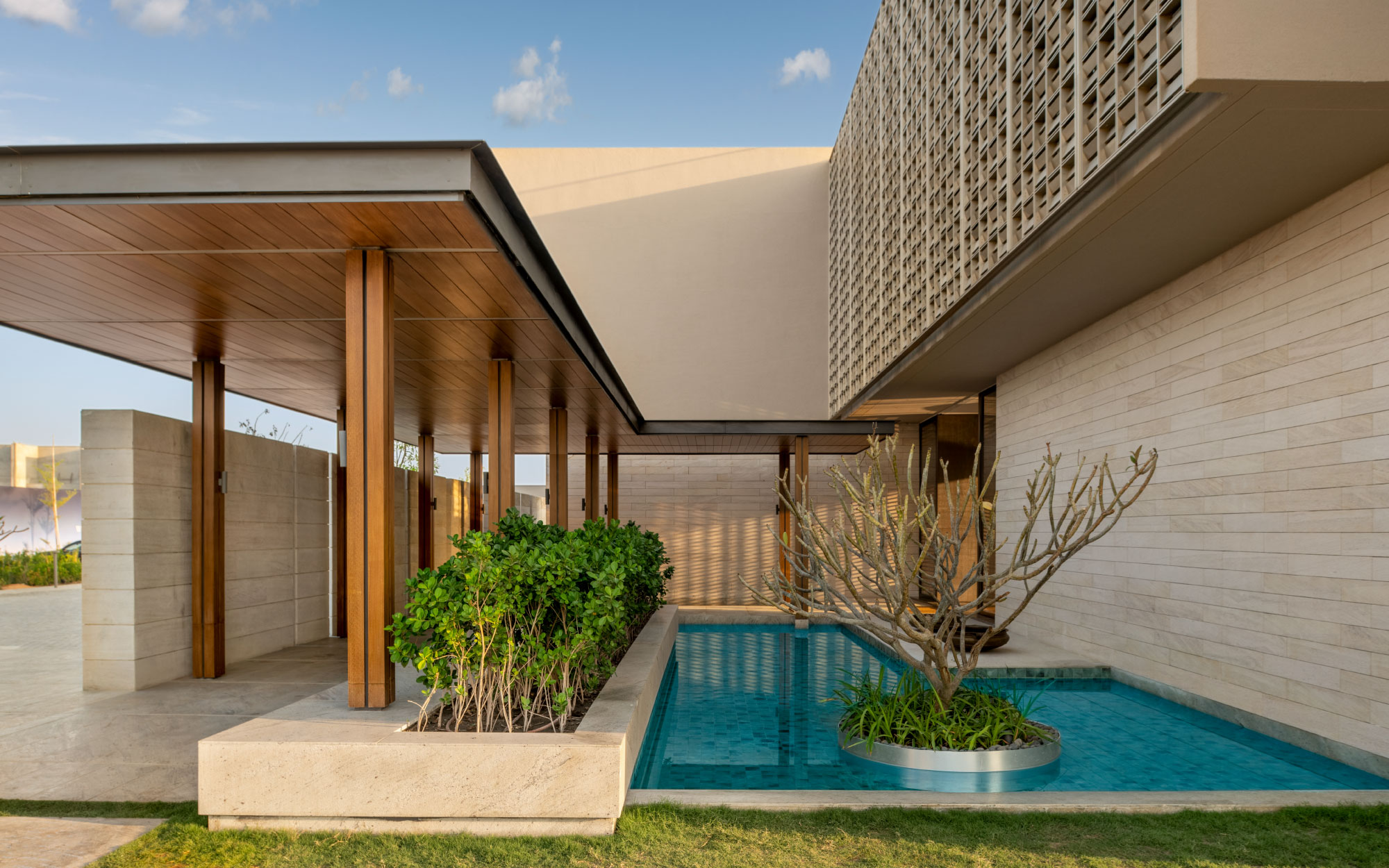 Framed by reflective pools and lush planting, the entry courts serve as contemplative pauses between the landscape and the villa. (Image Credits: Suryam Developers)

