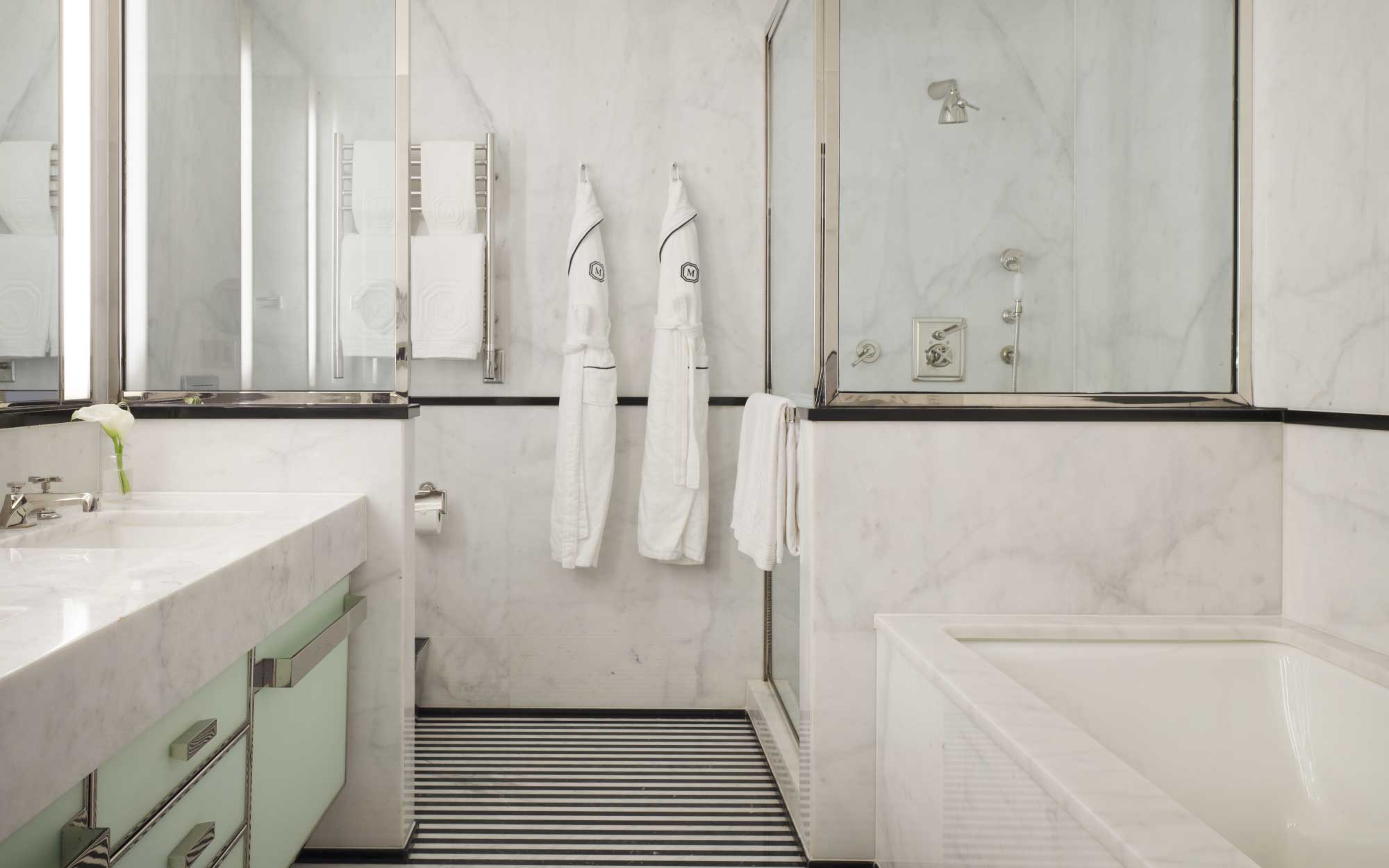 The bathroom mirrors the lobby’s black and white flooring and is paired with mint cabinets and deep soaking tubs for the perfect relaxation. (Image Credits: Adrian Gaut)
