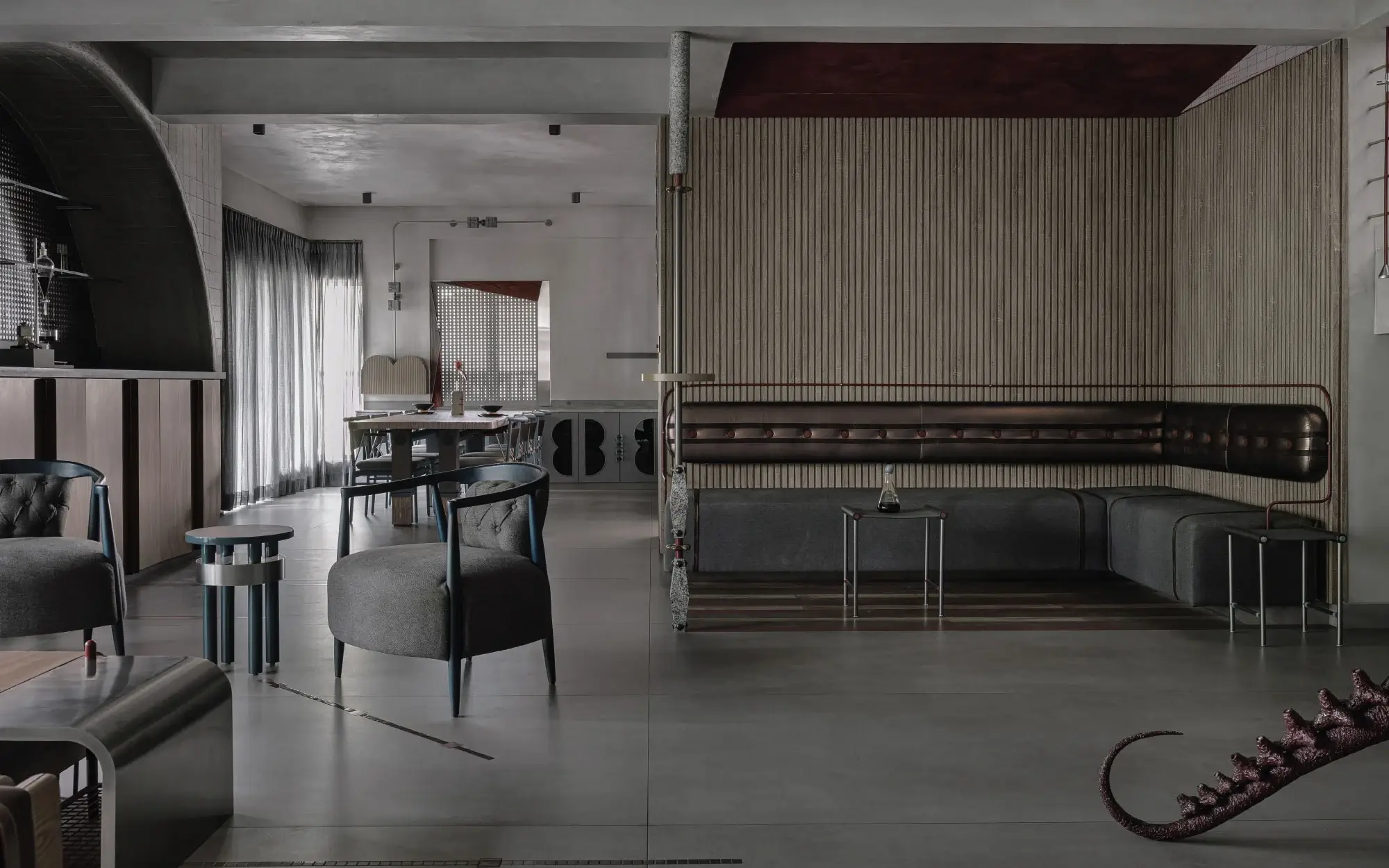 Opposite the bar, a levitating L-shaped couch and a sculptural stand-and-sip table layered with wood, stone, and metal details create an intimate setting for lingering cocktails and conversation. (Image Credits: Ishita Sitwala)