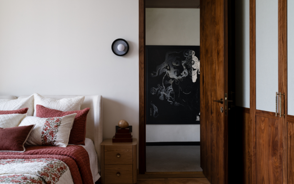 A customised wall light illuminates the daughter’s bedroom, finished with Opulo flooring and Sarita Handa linens. An artwork from the client’s personal collection animates the adjoining corridor. (Image Credits: Avesh Gaur)
