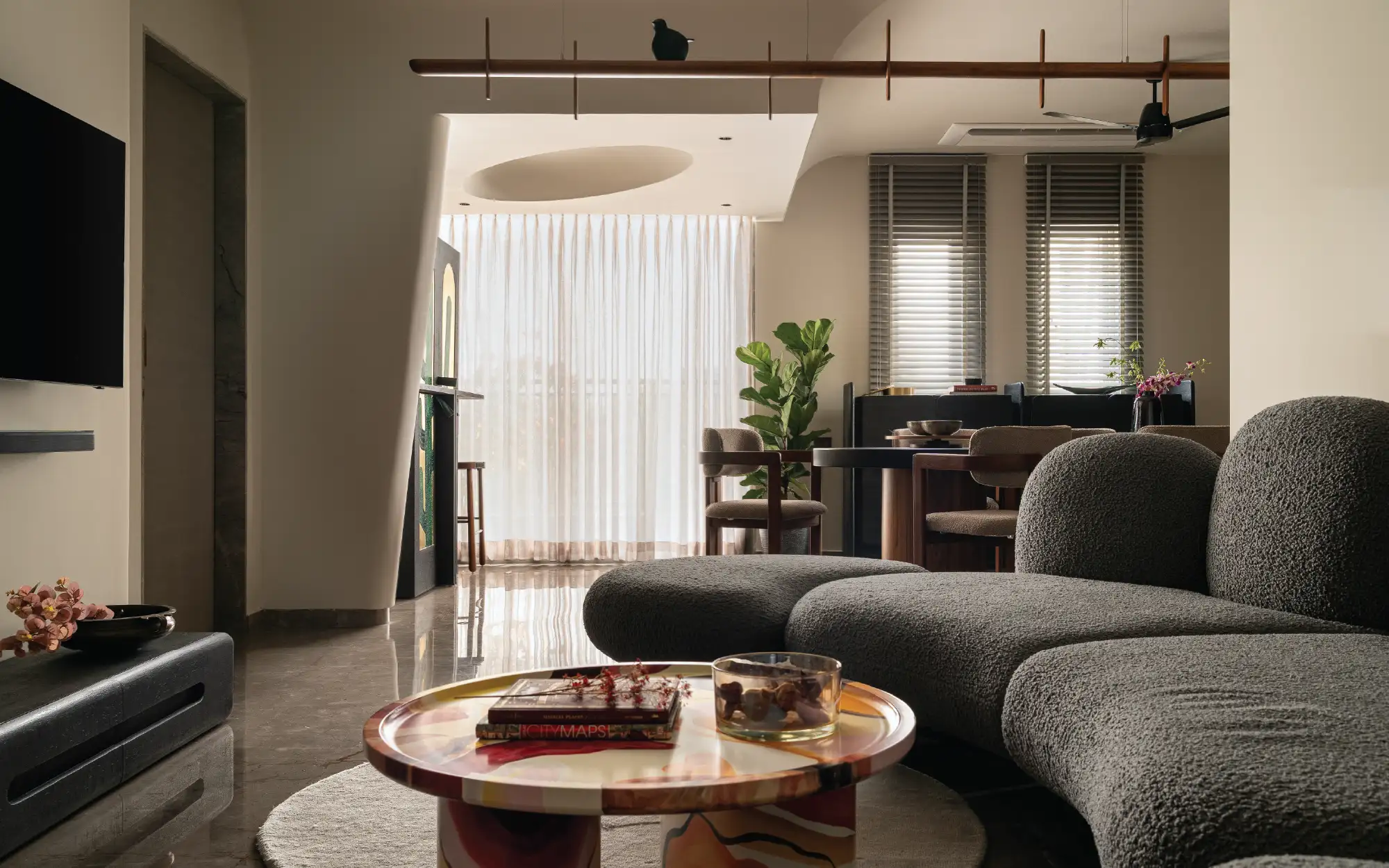 In the living room, an oversized imported couch and sculptural centre table set the tone for the home’s soft contours. (Image Credits: Yash R Jain)