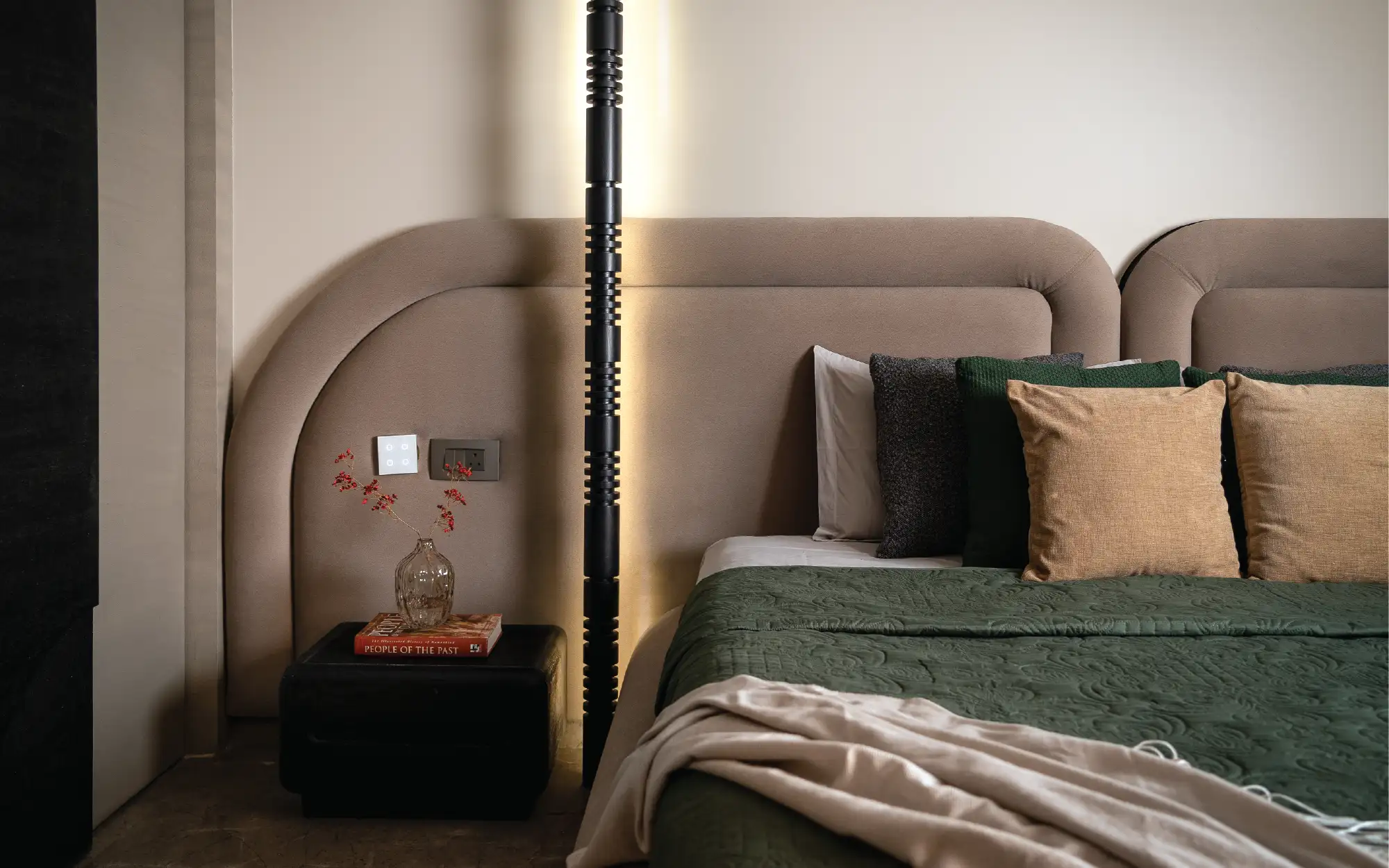Left: Warm oak detailing and muted olive tones shape the master bedroom into a quieter setting, where custom backlit spindles introduce a sculptural intervention behind the bed. (Image Credits: Yash R Jain) Right: Soft daylight and tactile finishes shape the master bedroom into a calm retreat, balancing the apartment’s playful moments with restraint. (Image Credits: Yash R Jain)